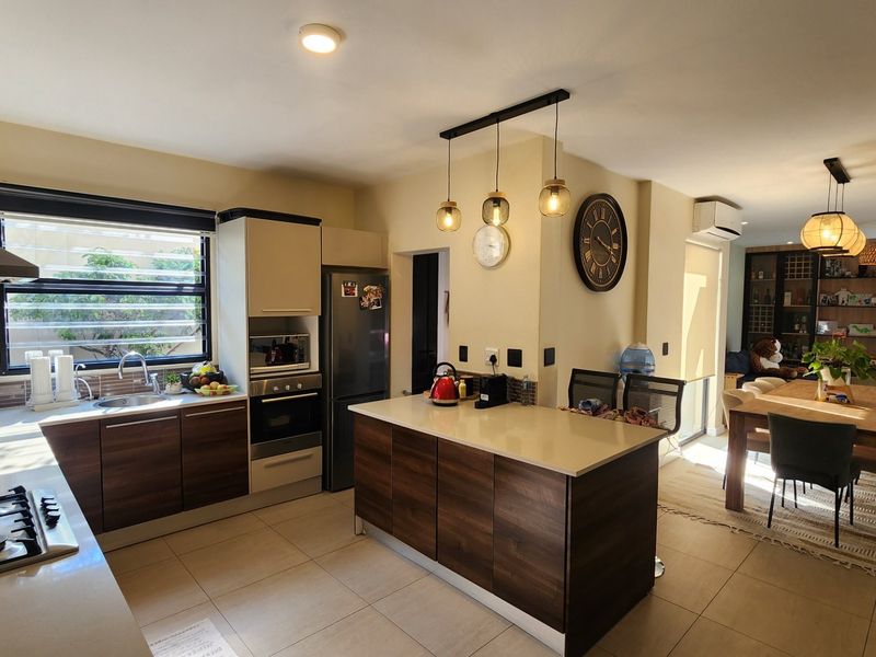 Spacious open-plan kitchen and dining area featuring modern cabinetry, a central island with stone countertops, and integrated appliances, perfect for contemporary living.