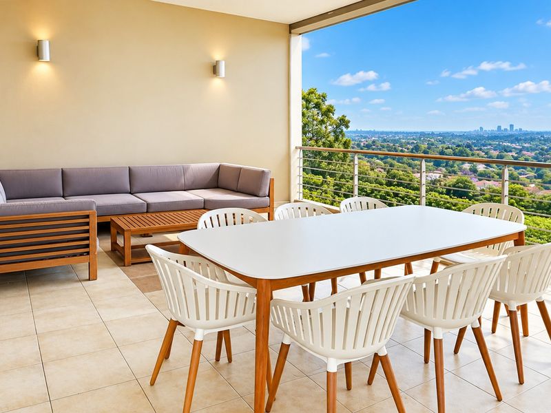Spacious covered balcony featuring tiled flooring, modern wall lighting, and a stainless steel balustrade with expansive elevated views.