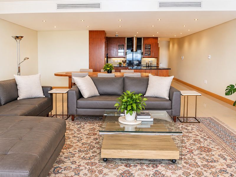 Spacious open-plan living and dining area featuring a modern kitchen with wooden cabinetry, stone countertops, and integrated ducted air conditioning.