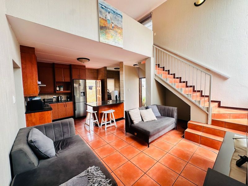 Open-plan living area featuring a kitchen with granite countertops, tiled flooring, and a staircase leading to an upper level.