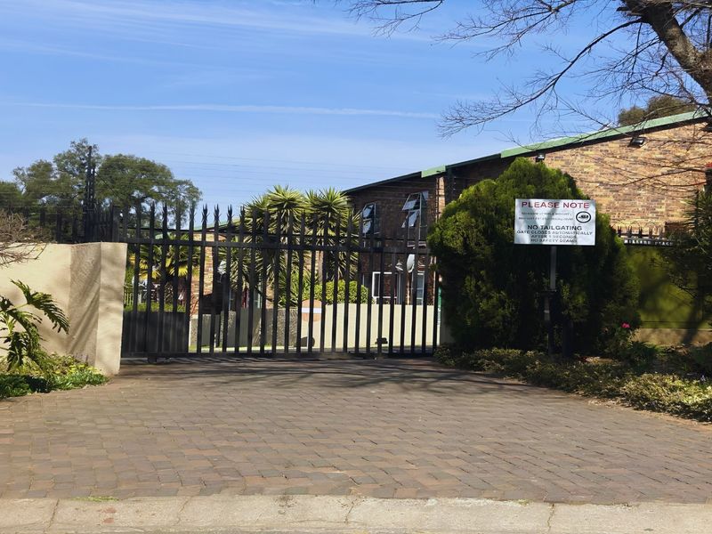 A secure gated entrance to an apartment complex featuring a paved driveway and brick building facade.