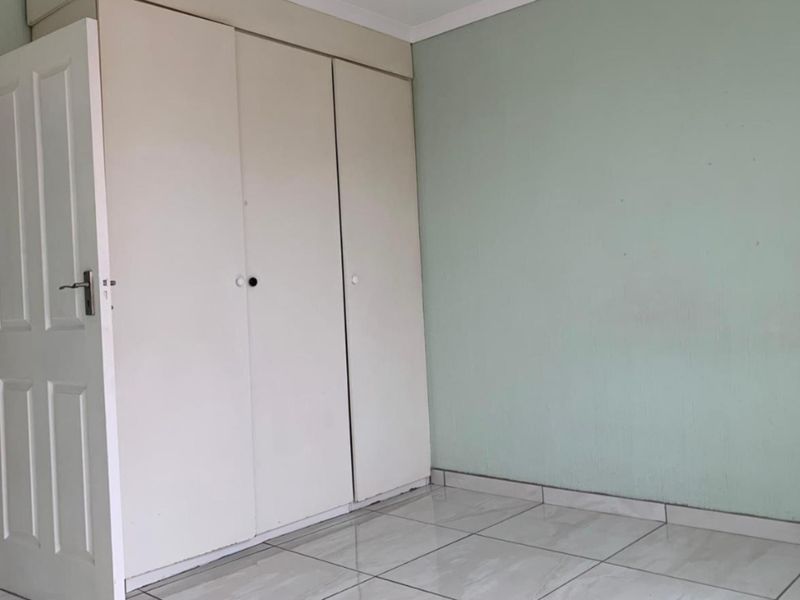 An empty bedroom featuring neutral tiled flooring and built-in cupboards, providing a blank canvas for personalization.