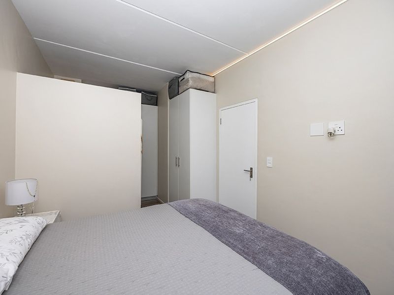A functional bedroom featuring a built-in wardrobe, neutral wall finishes, and standard electrical fixtures.