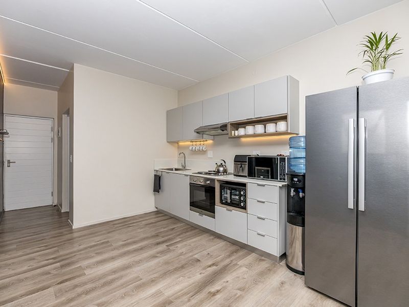 Modern kitchen featuring sleek grey cabinetry, integrated stainless steel appliances, under-cabinet lighting, and durable laminate flooring in an open-plan layout.