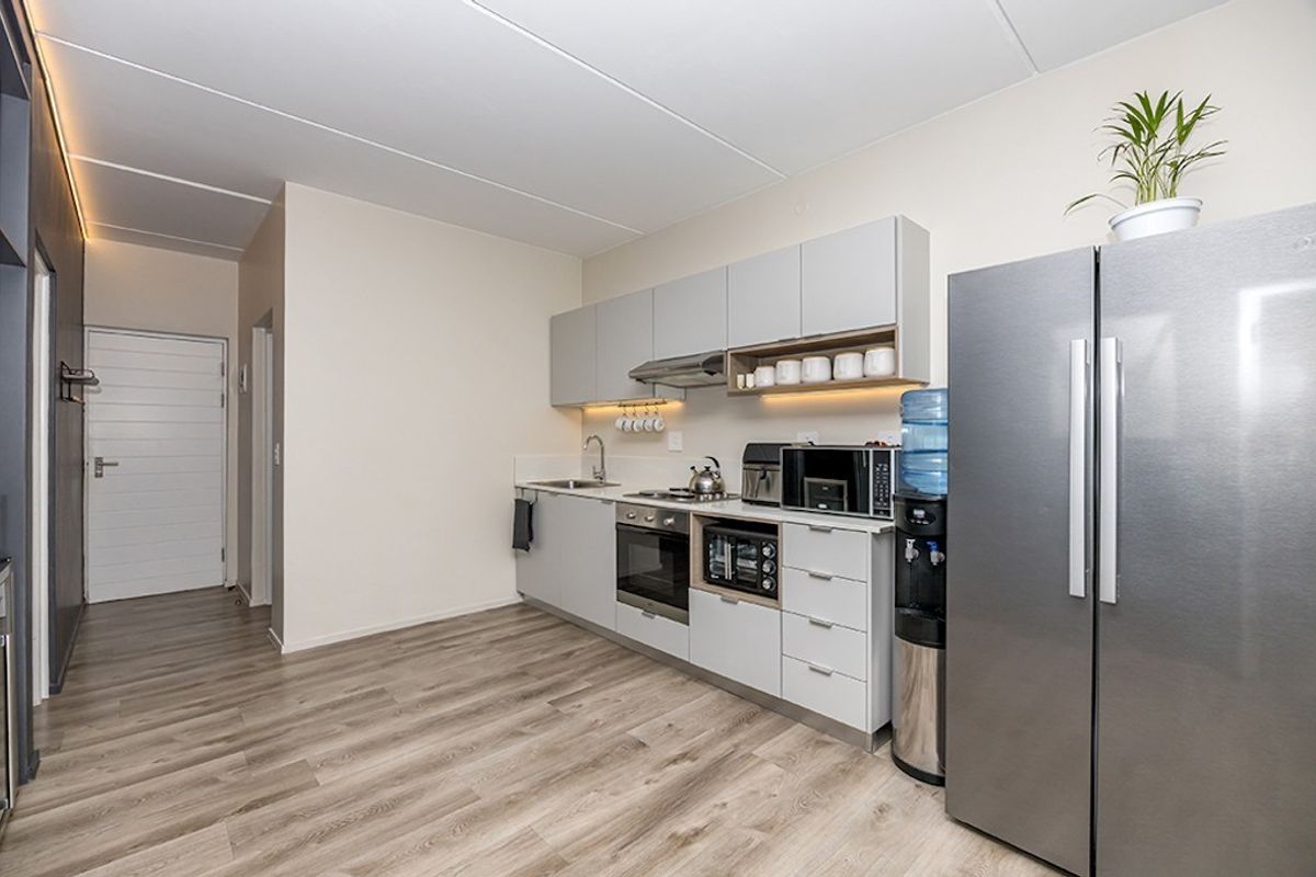 Modern kitchen featuring sleek grey cabinetry, integrated stainless steel appliances, under-cabinet lighting, and durable laminate flooring in an open-plan layout.