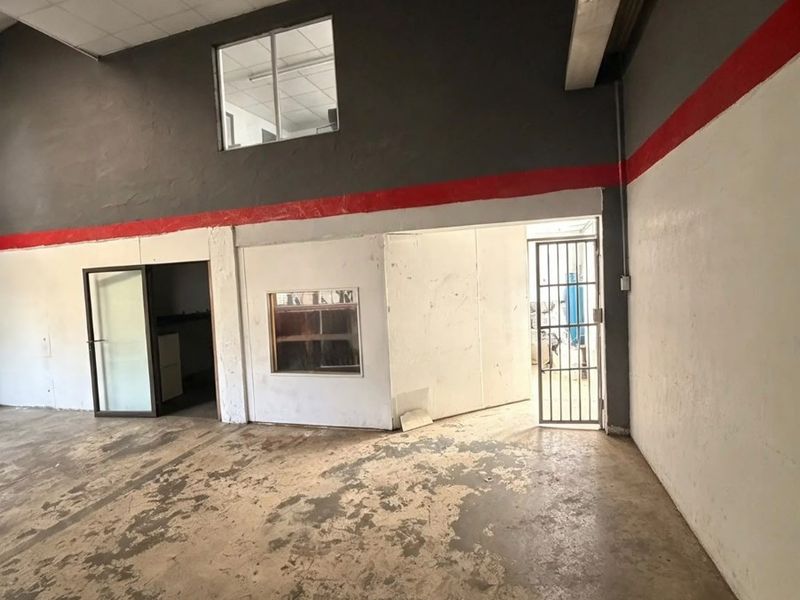 An open-plan utility or industrial space featuring concrete flooring, high ceilings, and internal security access points, suitable for commercial or workshop use.