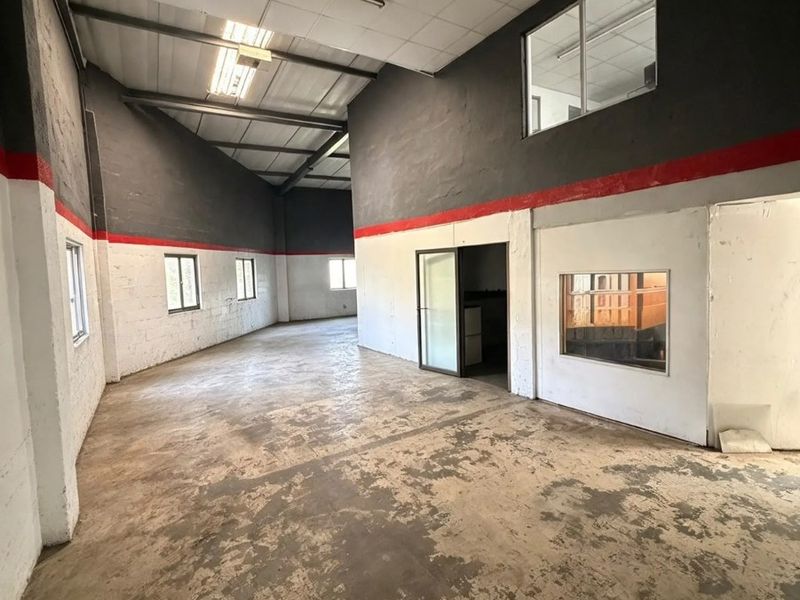 Spacious open-plan commercial unit featuring high ceilings, industrial concrete flooring, and internal office windows, offering a versatile blank canvas for business operations.
