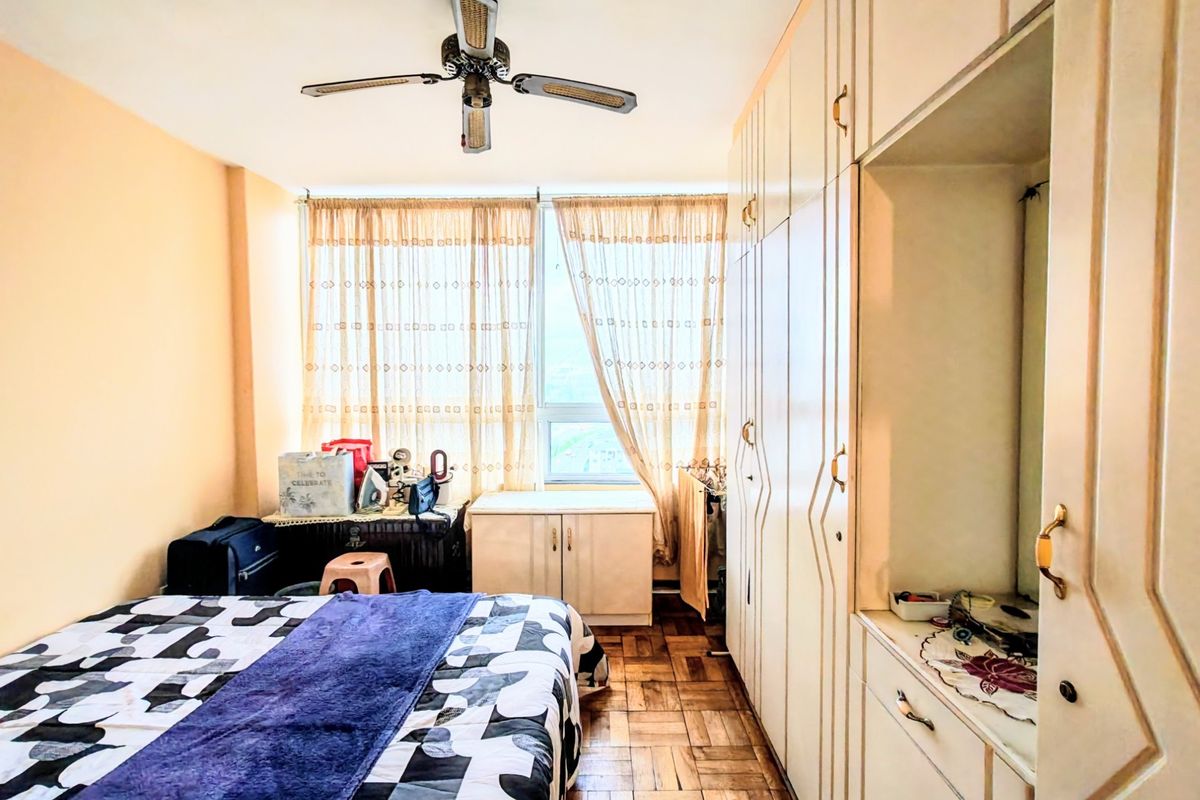 A bedroom featuring parquet flooring, a ceiling fan, and extensive built-in wardrobe storage with a vanity section.