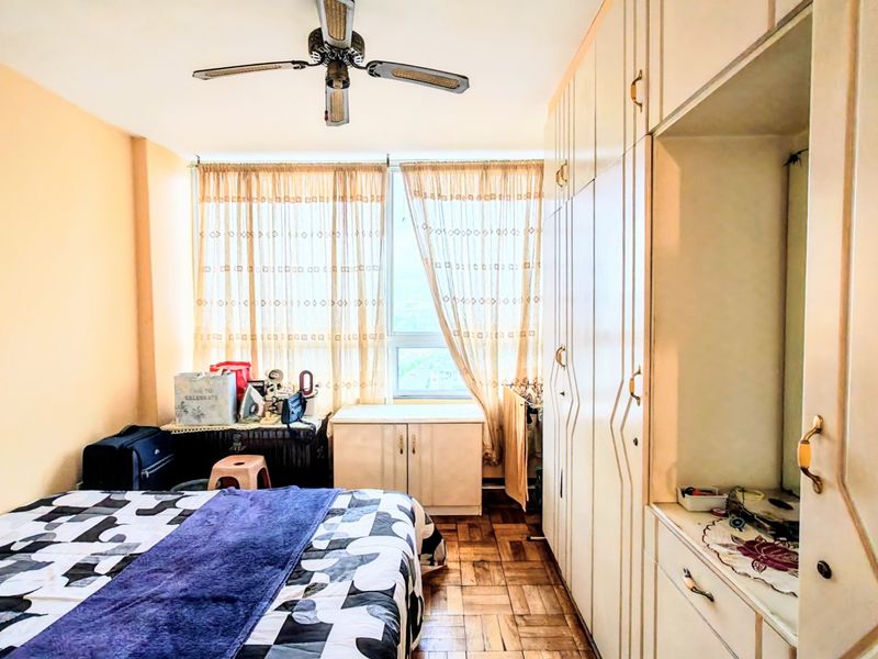 A bedroom featuring parquet flooring, a ceiling fan, and extensive built-in wardrobe storage with a vanity section.