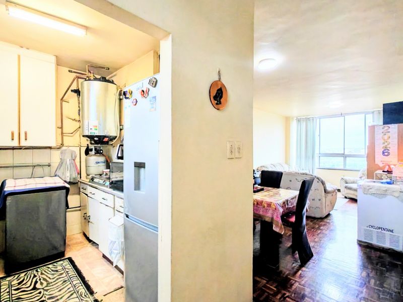 Open plan living and kitchen area featuring parquet flooring, built-in cabinetry, and an exposed water heater system in the kitchen section.
