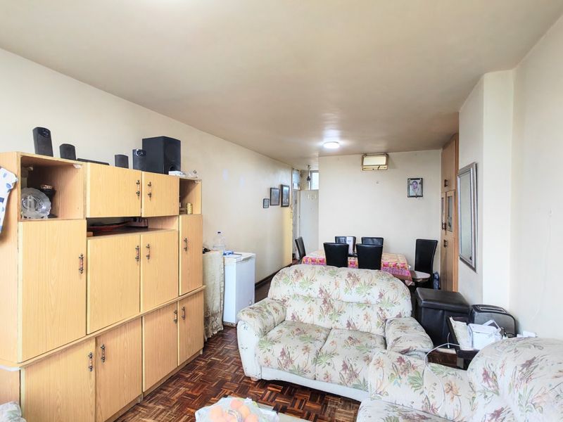 Open-plan living and dining area featuring parquet flooring, built-in storage cabinetry, and an integrated air conditioning unit.
