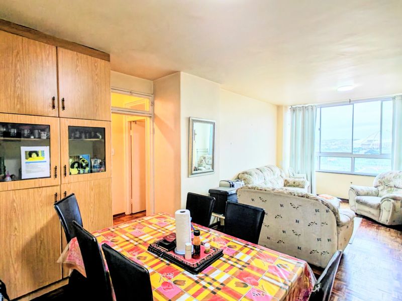 Open-plan living and dining area featuring parquet flooring, built-in cabinetry, and large windows providing natural light and views.