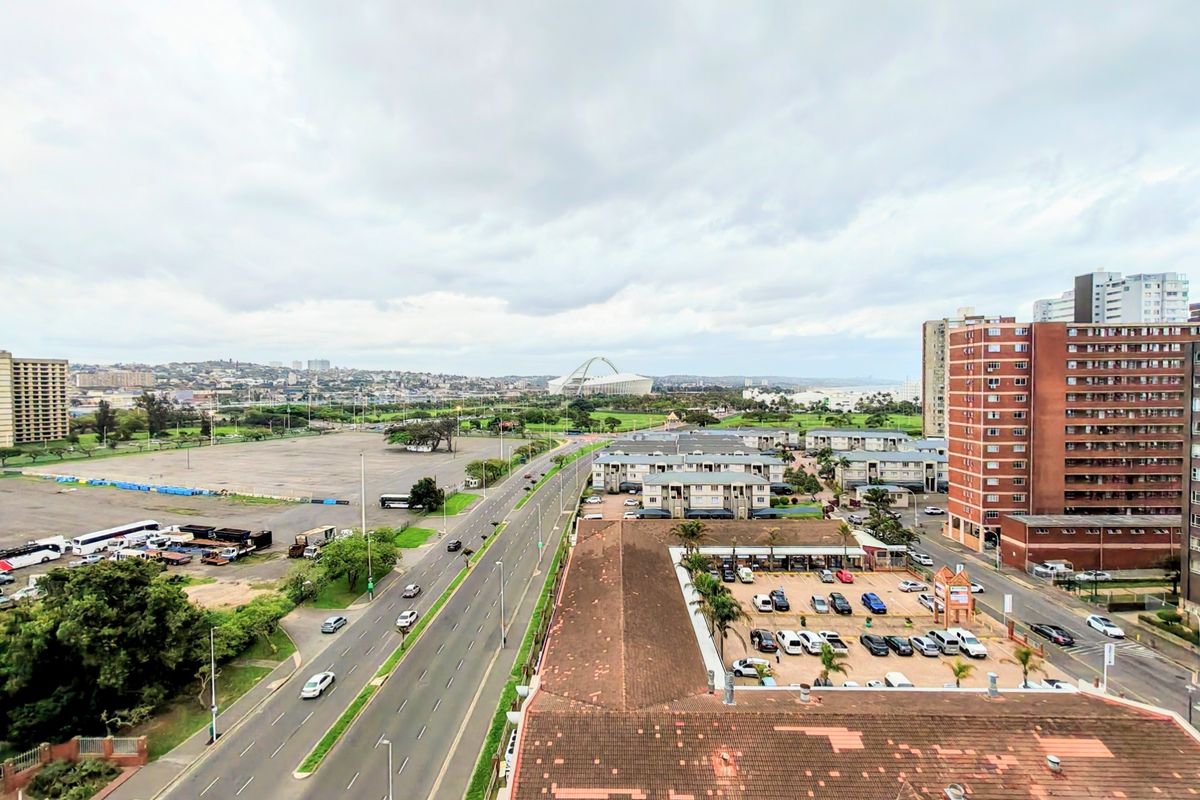 An elevated aerial view of the surrounding urban landscape, featuring nearby roads, residential apartment blocks, and a distant stadium.