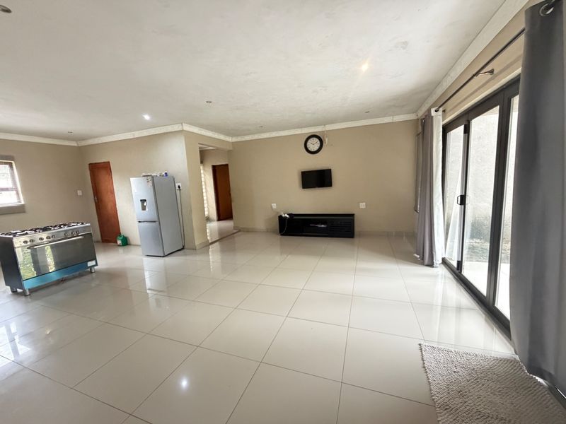 Spacious open-plan living area featuring large format floor tiles, recessed lighting, and sliding glass doors providing access to the exterior.