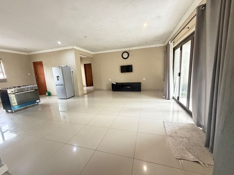 Spacious open-plan living area featuring large format floor tiles, recessed lighting, and sliding glass doors providing access to the exterior.