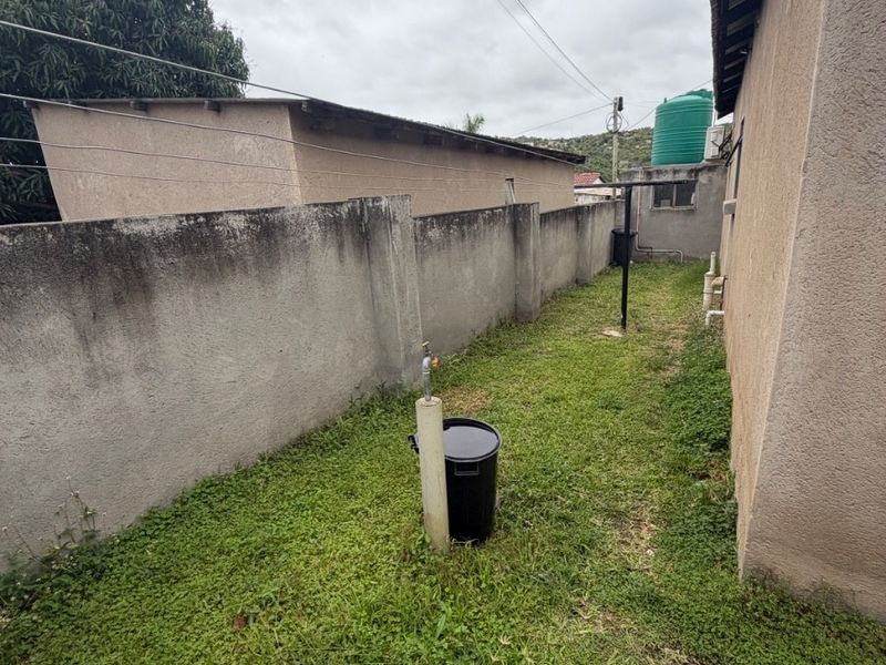 A narrow rear yard area featuring a boundary wall, an outdoor water tank, and a fixed washing line, requiring landscaping and maintenance.