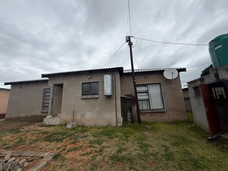 Rear view of the property featuring a solar geyser, water storage tank, and aluminium window frames with security bars.