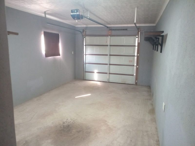 A clean, empty single-car garage featuring concrete flooring, an automated sectional door, and wall-mounted storage brackets.