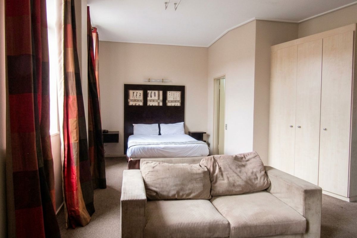 A bedroom featuring built-in wardrobes and carpet flooring, showing signs of ceiling water staining that may require maintenance.