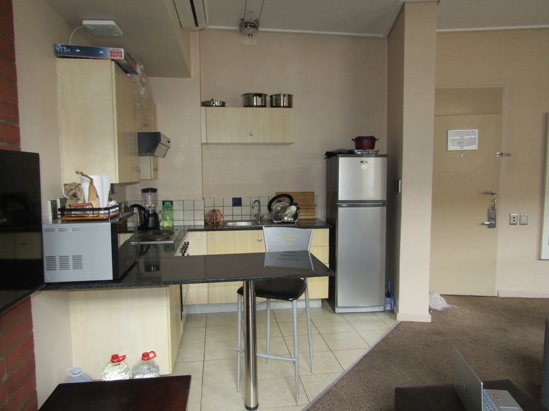 Compact kitchen featuring light wood cabinetry, granite countertops, tiled backsplash, and integrated appliances, designed for efficient use in an apartment setting.