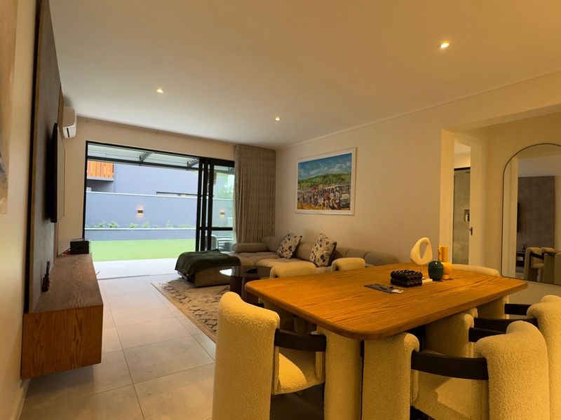 Modern open-plan living and dining area featuring tiled floors, recessed lighting, and large sliding glass doors providing seamless access to the outdoor patio.