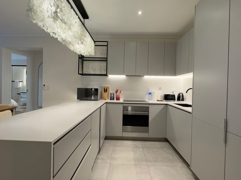 Modern, well-appointed kitchen featuring sleek handleless cabinetry, quartz countertops, integrated appliances, and stylish under-cabinet lighting, creating a clean and functional culinary space.