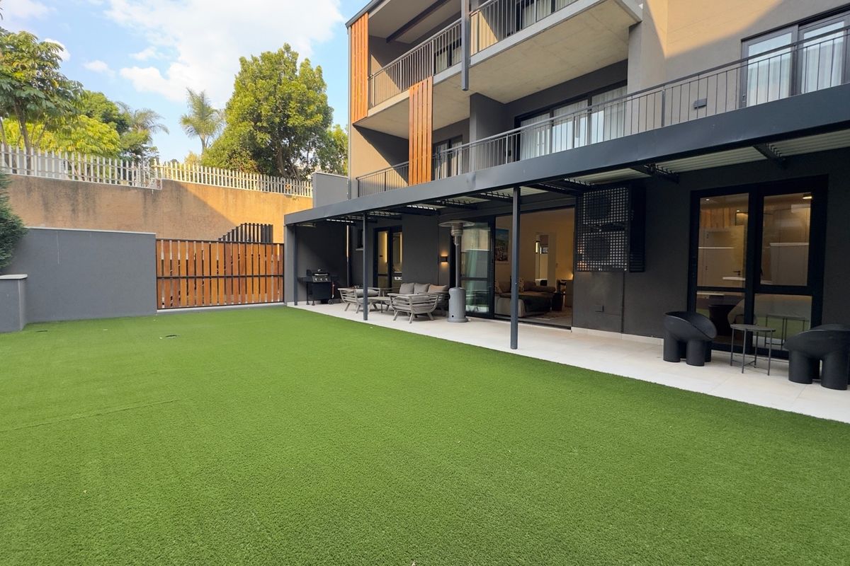 A modern ground-floor apartment featuring a private garden with artificial lawn and a covered patio area with direct access to the living space.