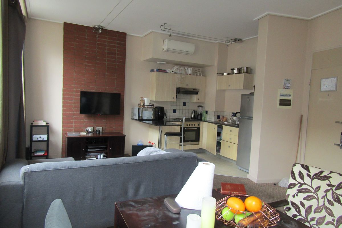 Open-plan living and kitchen area featuring an exposed brick wall, functional cabinetry, and a split-system air conditioner.