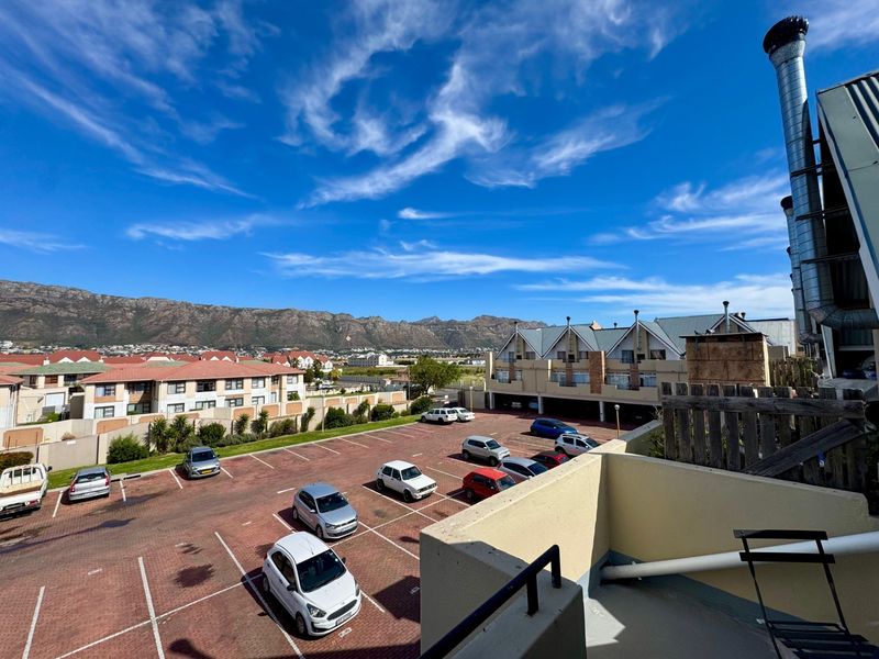 Elevated view overlooking the apartment complex parking area with mountain vistas in the background.