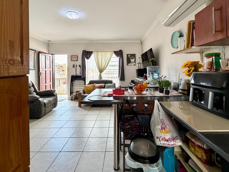 Open-plan living area featuring tiled flooring, a split-system air conditioner, and a functional kitchen space with built-in cabinetry and countertops.