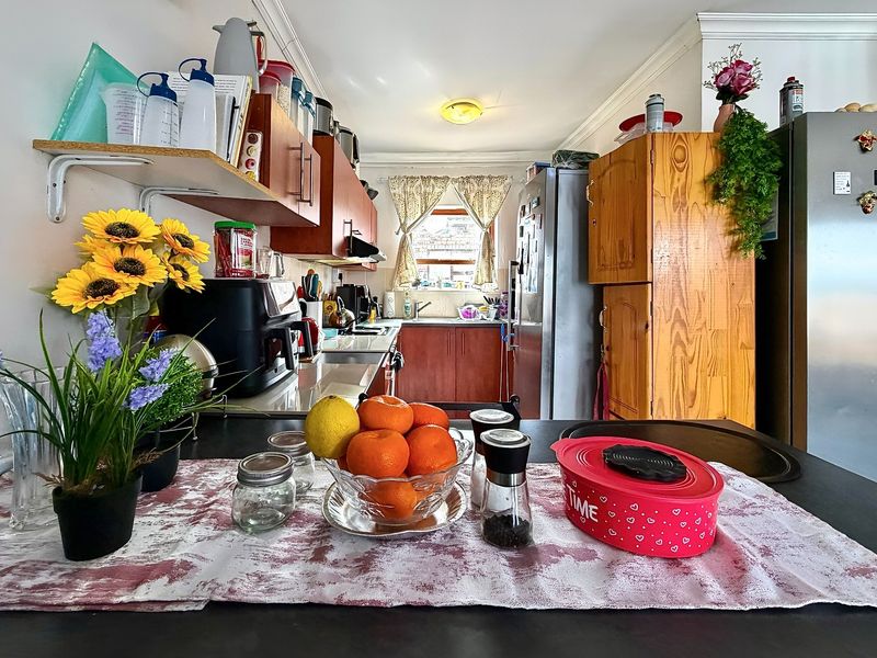 A functional kitchen featuring built-in cabinetry, laminate countertops, and a stainless steel sink, offering a practical layout with potential for modern updates.