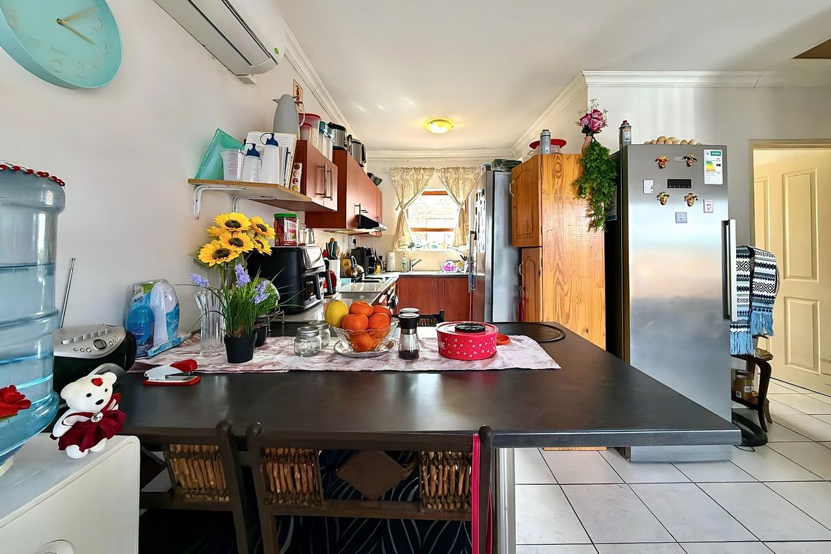 A functional kitchen featuring tiled flooring, built-in cabinetry, laminate countertops, and a split-system air conditioner, offering a practical layout for daily use.