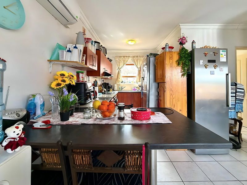 A functional kitchen featuring tiled flooring, built-in cabinetry, laminate countertops, and a split-system air conditioner, offering a practical layout for daily use.