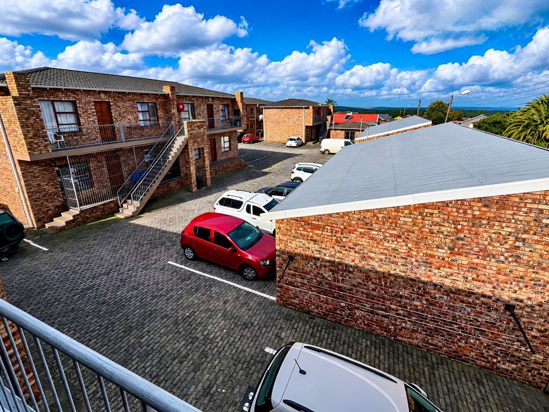 Elevated view of an apartment complex courtyard featuring face brick buildings, corrugated metal roofing, and a paved parking area.