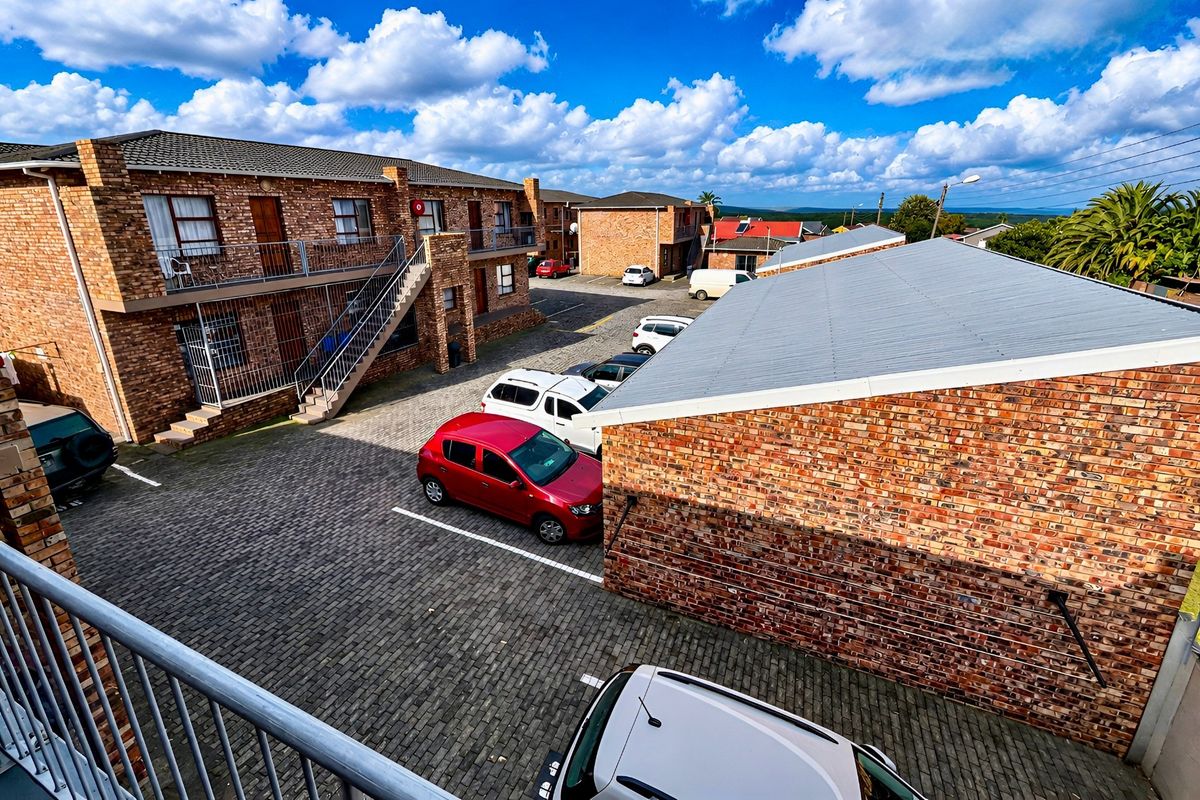 Elevated view of an apartment complex courtyard featuring face brick buildings, corrugated metal roofing, and a paved parking area.
