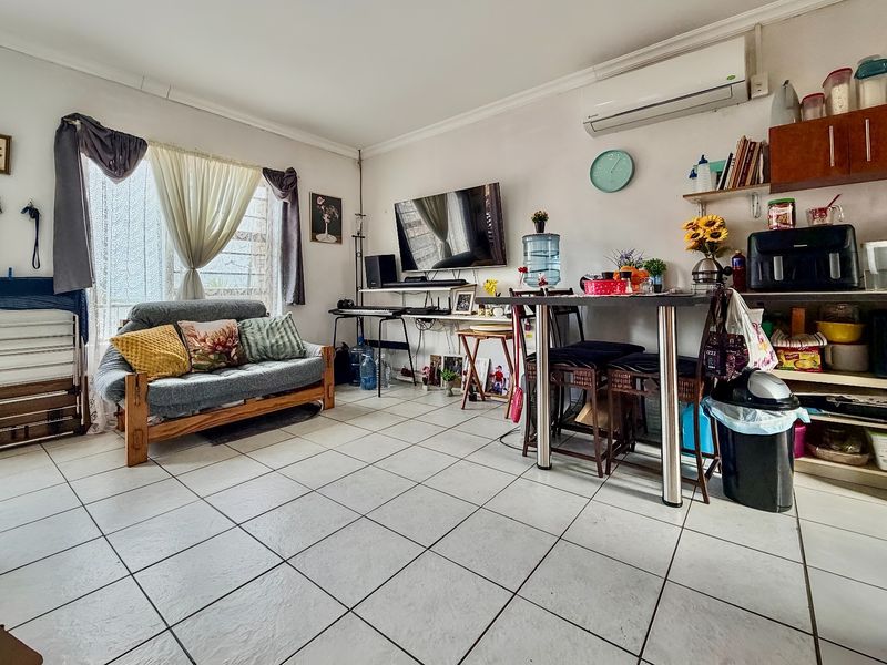 Open-plan living area featuring tiled flooring and a wall-mounted air conditioning unit, offering a versatile space for dining and relaxation.