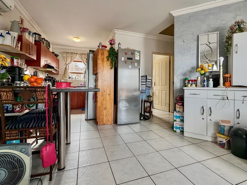 Open plan kitchen and living area featuring tiled flooring, built-in cabinetry, and an air conditioning unit, offering a functional layout for daily living.