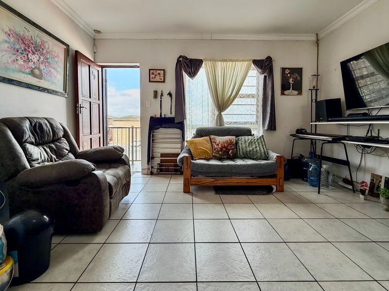 A living room featuring tiled flooring and direct access to an outdoor balcony area through a sliding door.