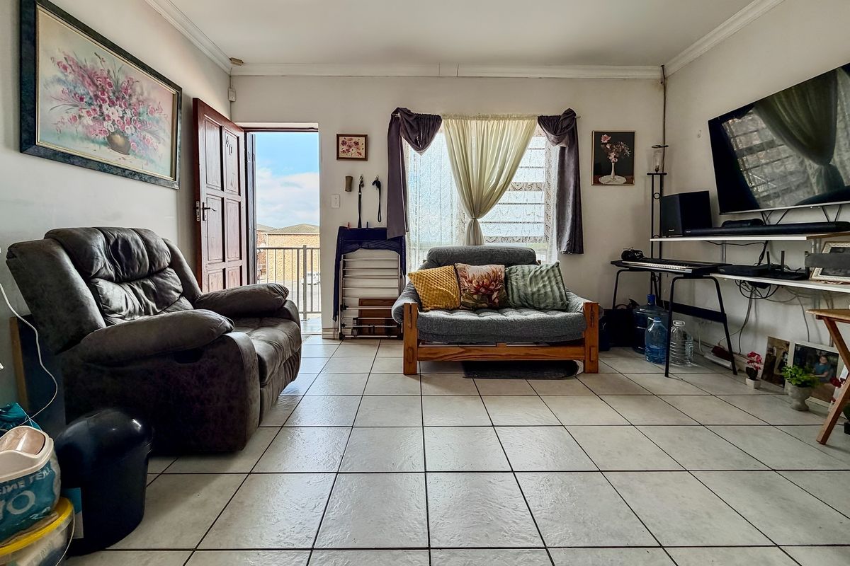 A living room featuring tiled flooring and direct access to an outdoor balcony area through a sliding door.