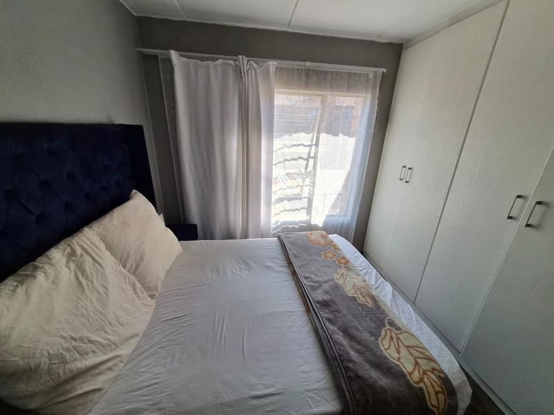 A bedroom featuring built-in cupboards and a window with natural light.