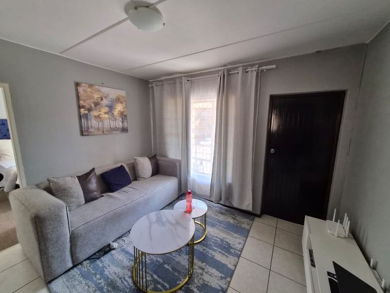 A living room featuring tiled flooring and neutral wall tones, providing a functional and comfortable space for relaxation.