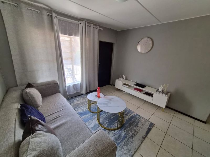 A well-lit living room featuring neutral grey walls and tiled flooring, providing a comfortable and functional space for relaxation.