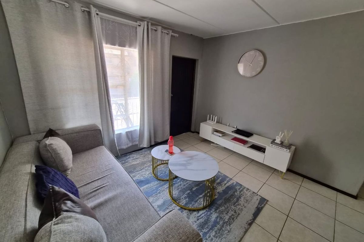 A well-lit living room featuring neutral grey walls and tiled flooring, providing a comfortable and functional space for relaxation.