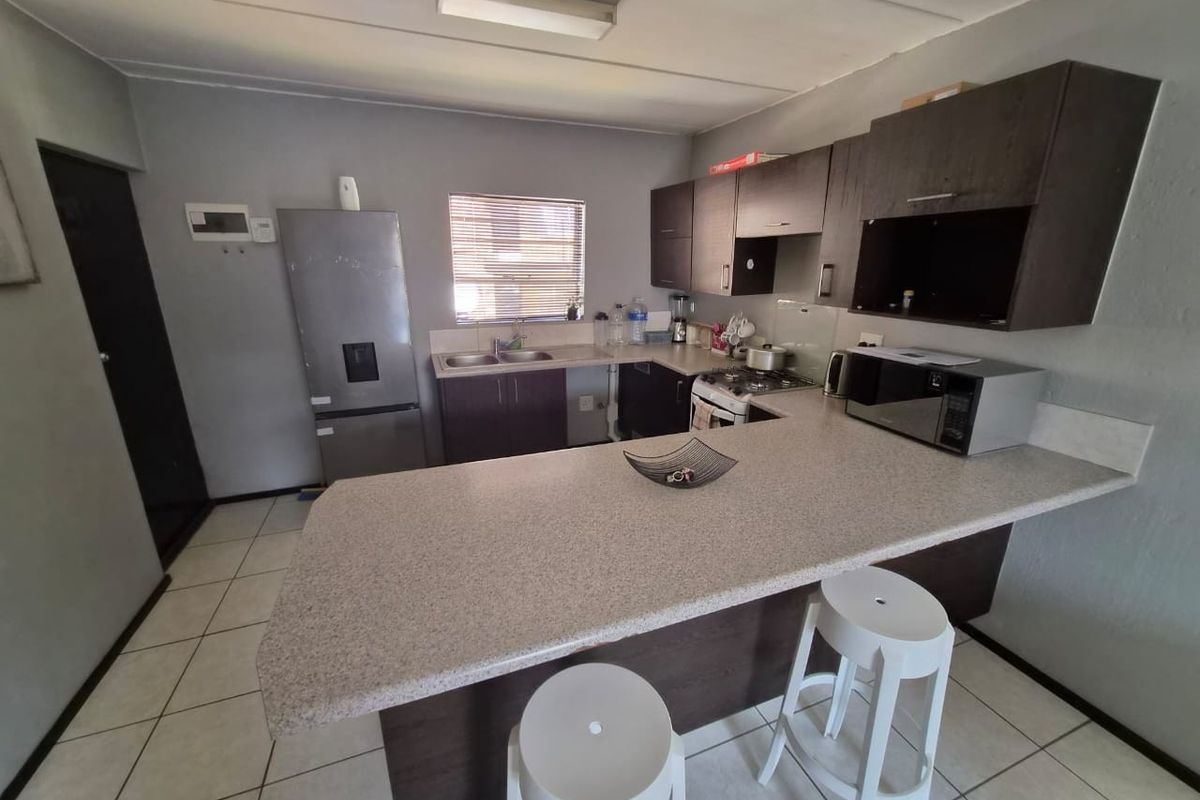 Functional kitchen featuring dark cabinetry, laminate countertops, a breakfast bar, and tiled flooring, providing a practical layout for daily meal preparation.