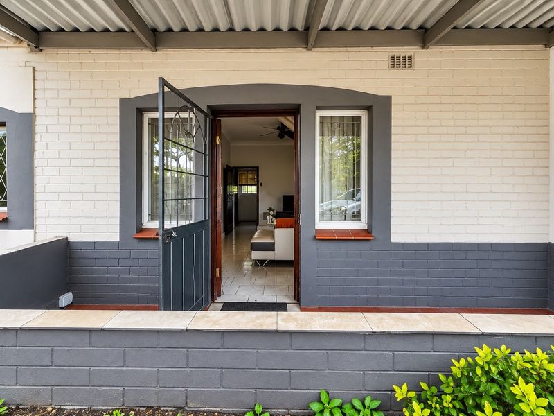 A covered patio area featuring a painted brick facade, security gate, and tiled ledge, providing a transition into the interior living space.
