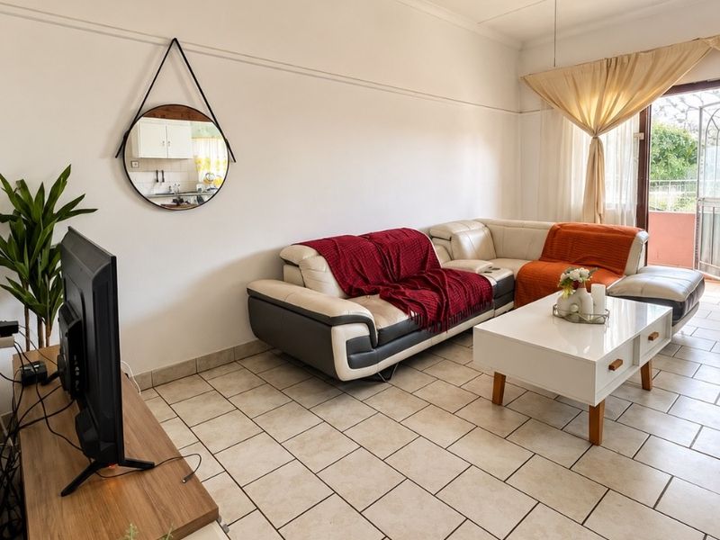 A living room featuring tiled flooring, a ceiling fan, and access to an outdoor area through a sliding glass door.