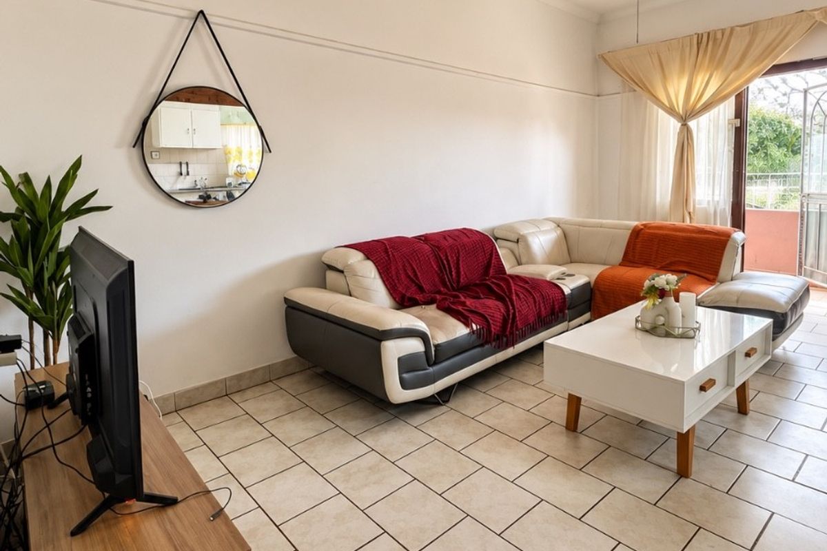 A living room featuring tiled flooring, a ceiling fan, and access to an outdoor area through a sliding glass door.