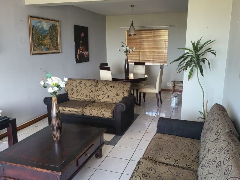 Open-plan living and dining area featuring tiled flooring, neutral wall tones, and natural light through venetian blinds.