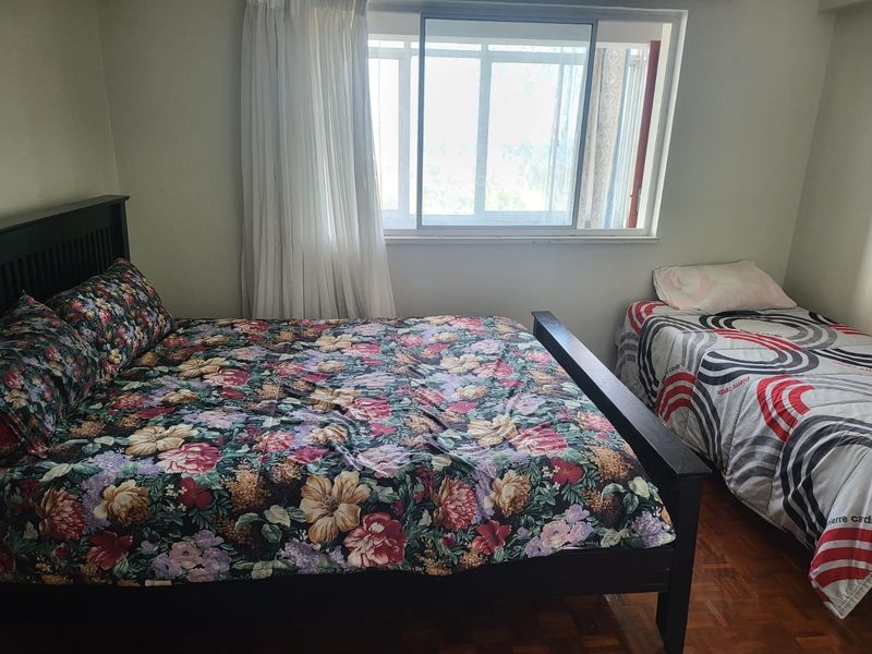 A bedroom featuring parquet flooring and a sliding window, providing a functional space with natural light.