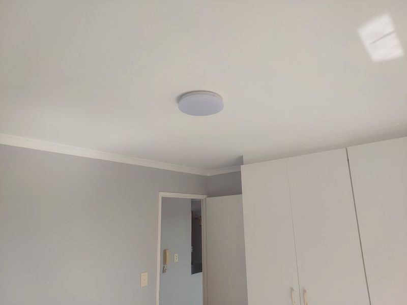 A clean, neutral bedroom featuring built-in cupboards, coving, and a ceiling-mounted light fixture, presenting a well-maintained and ready-to-occupy space.